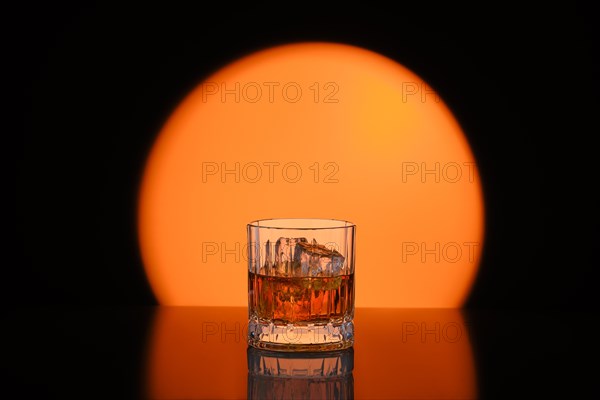 Low key photo of whiskey with ice in facetted rocks glass