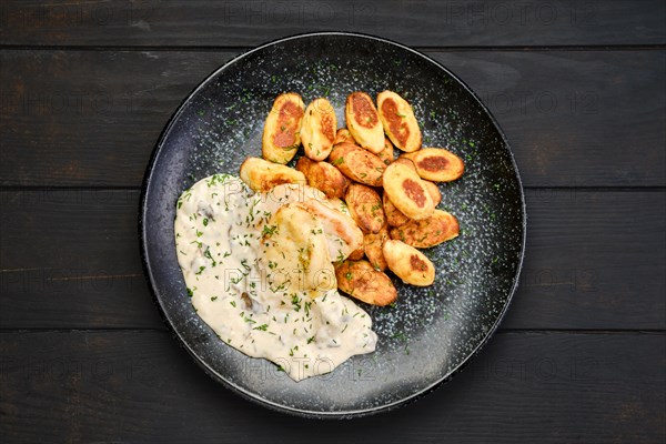 Top view of roasted chicken fillet with gnocchi and mushroom sauce