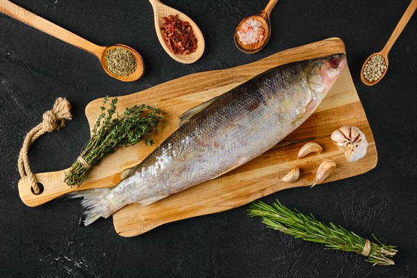 Overhead view of raw frozen unpeeled omul on wooden cutting board