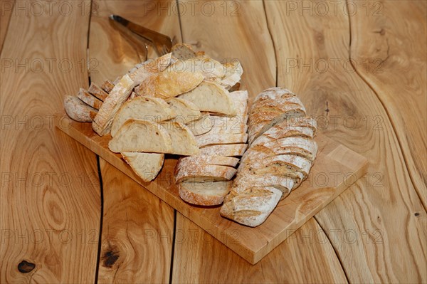 Cutted bread with seeds on board on rough wooden table