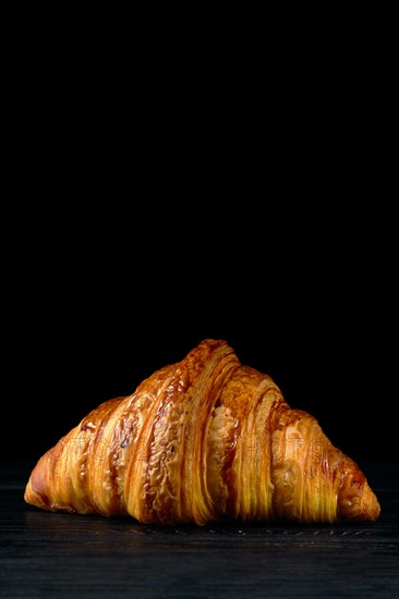Fresh golden croissant on black table