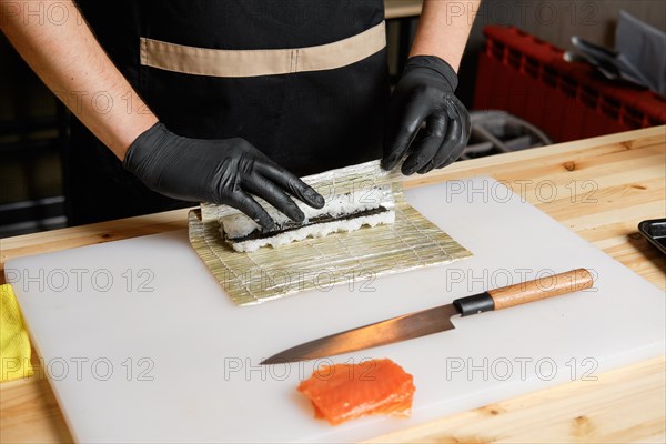 Hands of chef making salmon rolls