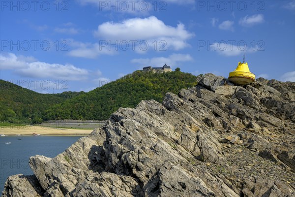 Dry buoy in front of Waldeck Castle at low water in Lake Edersee
