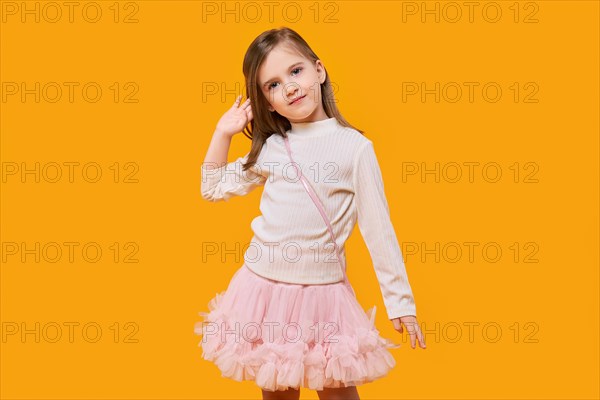 Cute little child posing on bright yellow background