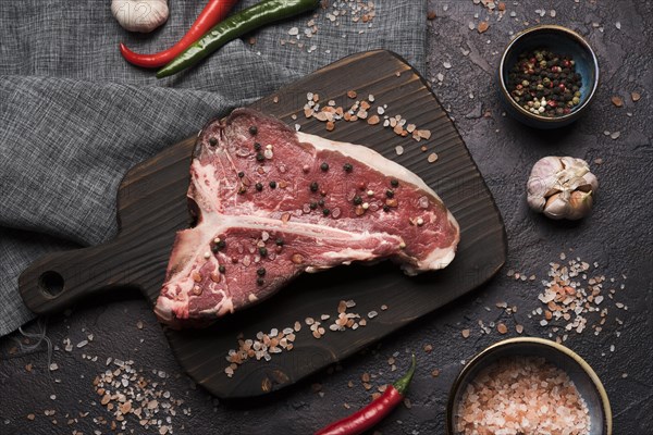 Flat lay raw t bone steak with pepper salt