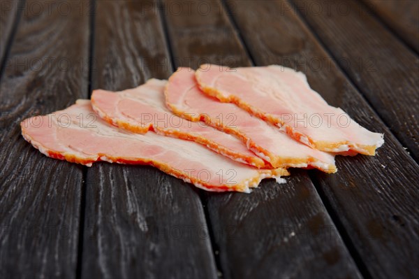 Selective focus photo of slices of fresh bacon on wooden table