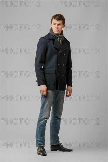 Full length portrait of handsome man in warm winter coat posing in studio