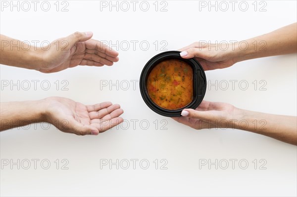 Hand giving bowl soup needy person