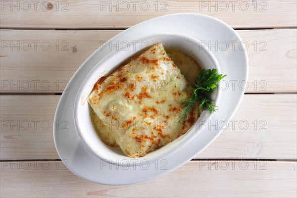 Thin pancakes with stuffing baked in oven with melted cheese
