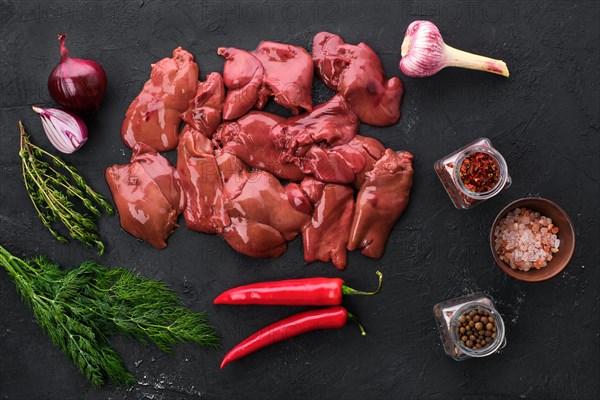 Top view of raw duck liver with spice on black concrete background