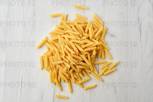 Overhead view of penne pasta on wooden background
