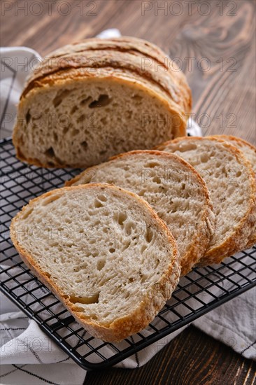 Closeup view of artisan whole grain wheat bread cut on slices on wooden table