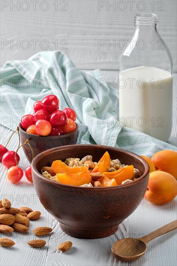 Muesli with apricots and almonds on white wooden table