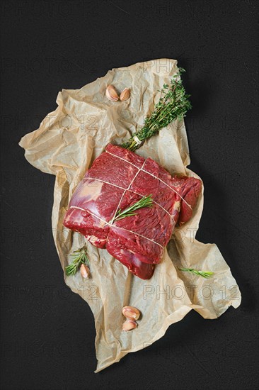 Overhead view of raw beef neck with garlic on wrapping paper