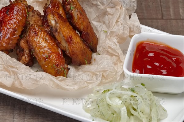 Closeup view of fried chicken wings with ketchup in wrapping paper