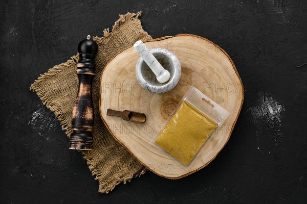 Wooden cross section with curry in plastic package and stone mortar and mill