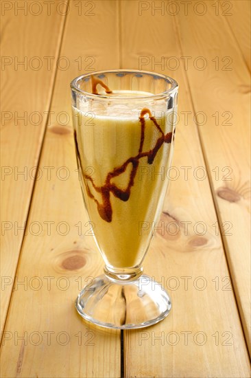 Glass of banana smoothie on wooden table