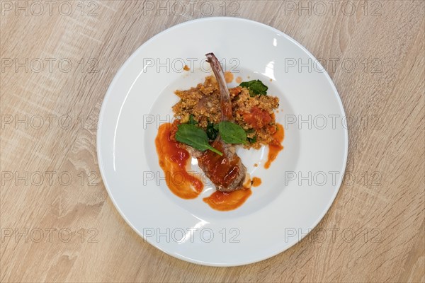 Top view of fried lamb rib with quinoa porridge on wooden table