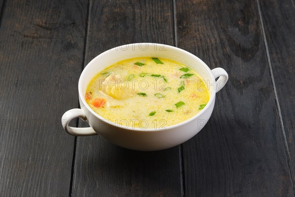 Bowl with hake soup with cream and carrot on a table