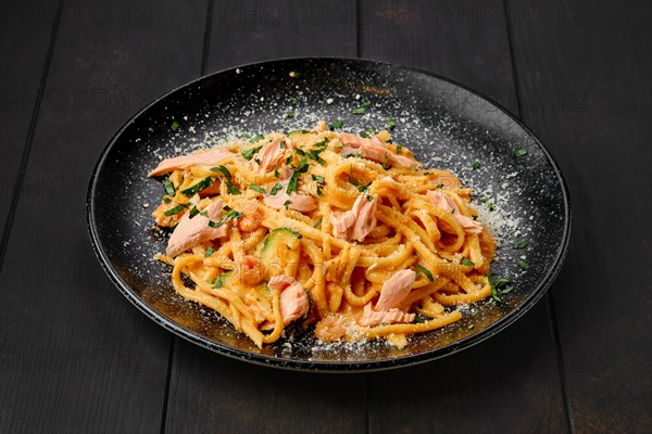 Pasta with salmon and zuccini with grated parmesan on a plate