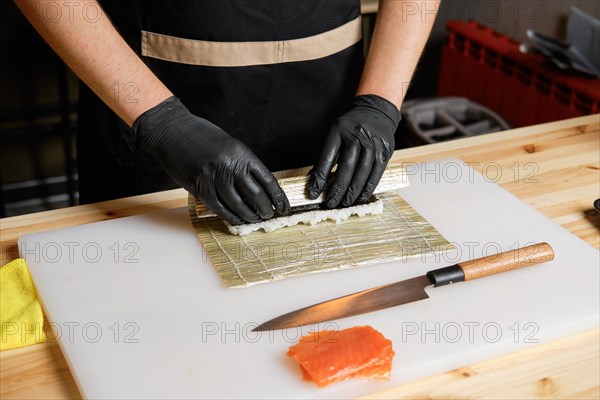 Hands of chef making salmon rolls