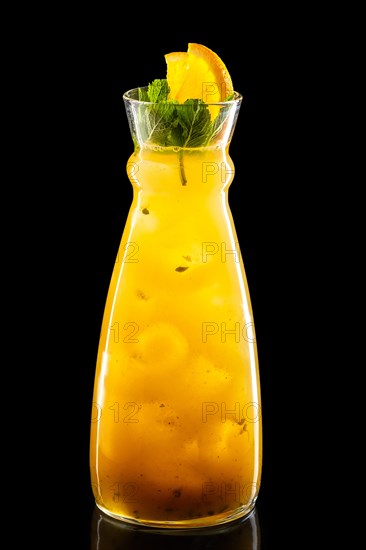 Pitcher with orange and passion fruit ice lemonade isolated on black background