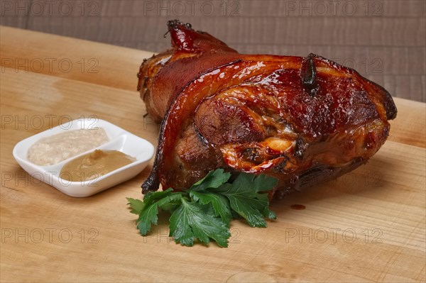 Roasted knuckle served with mustard and horseradish on wooden cutting board