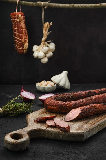 Smoked pork sausage with spices on wooden cutting board