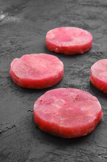 Fresh raw round tuna cutlet on wooden background