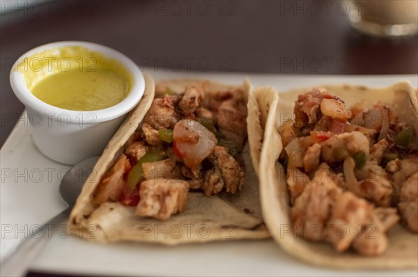 View of chicken tacos served on the table with sauce. Delicious Mexican chicken tacos with salsa and pico de gallo served on the table. Mexican tacos al pastor served with hot sauce