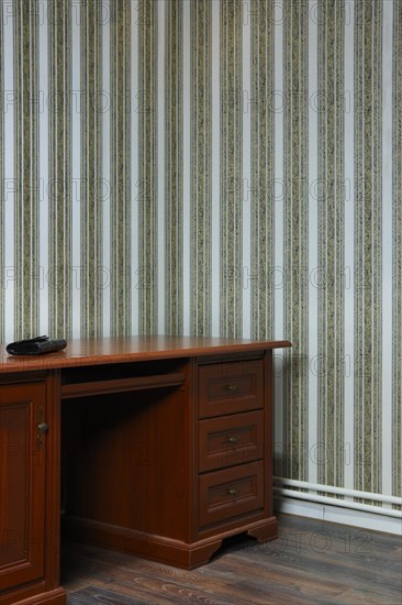 Old wooden table in the corner of the room with striped wallpaper