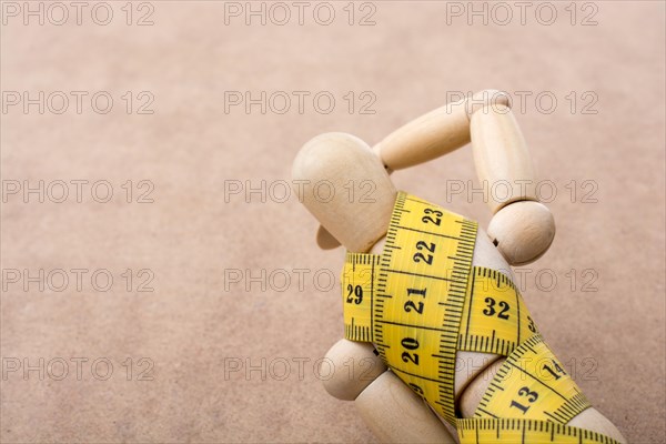 Yellow color measuring tape wrapped on wooden man