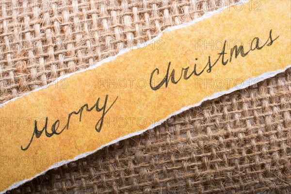 Merry Christmas wording written on a torn paper on canvas