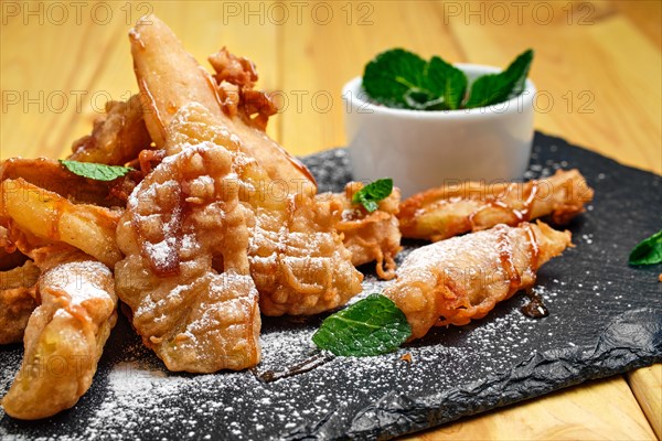 Close up view of deep fried fruits in breading served with caramel and strawberry jam