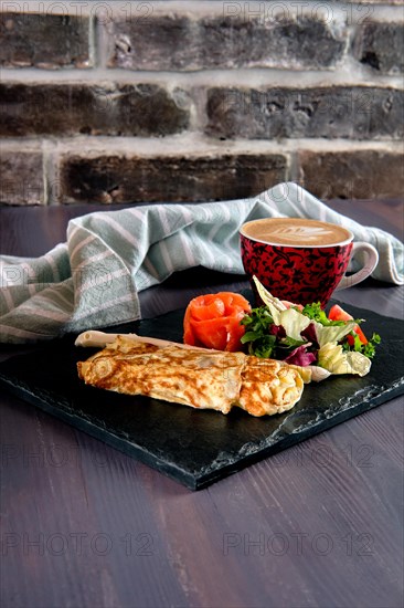 Omelette with salmon on slate plate and cup of latte