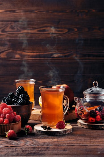 Freshly brewed fruit and herbal tea in kettle and two cups