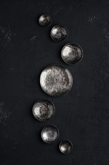 Composition with empty forged bowls of different size on black background