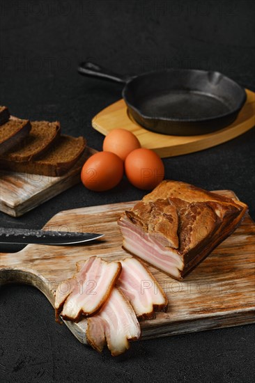 Smoked pork bacon with brown bread and eggs on wooden cutting board