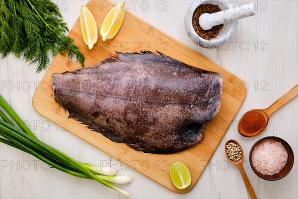 Top view of raw fresh halibut without head on wooden cutting board