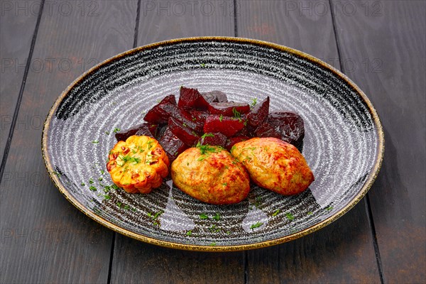 Plate with fried pork cutlet with roasted beetroot slices and grilled maize on dark wooden table