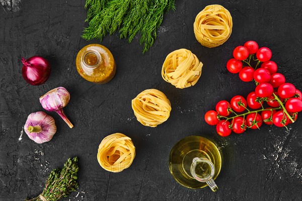 Overhead view of raw tagliatelle with spice and herbs on black background