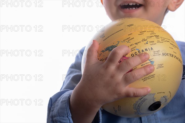 Baby with blue shirt holding a globe in hand on white background