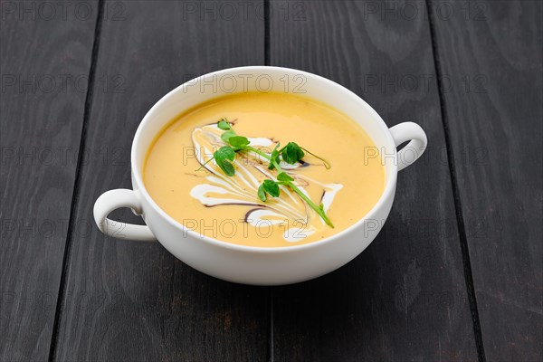 Portion of pumpkin puree soup with barbecue sauce and sour cream