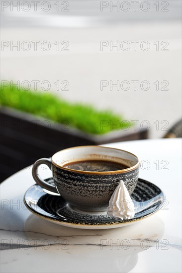 Cup of coffee on the edge of the table on outdoor terrace