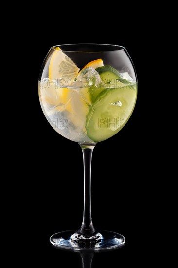 Big round wine glass with fresh cold lemonade isolated on black background