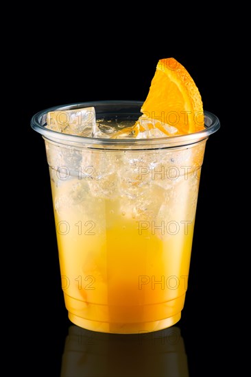 Cold fizz cocktail with orange in take away cup isolated on black background