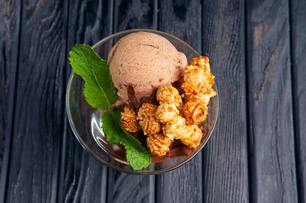 A cup of chocolate ice cream decorated with caramel popcorn and mint leaves. Top view