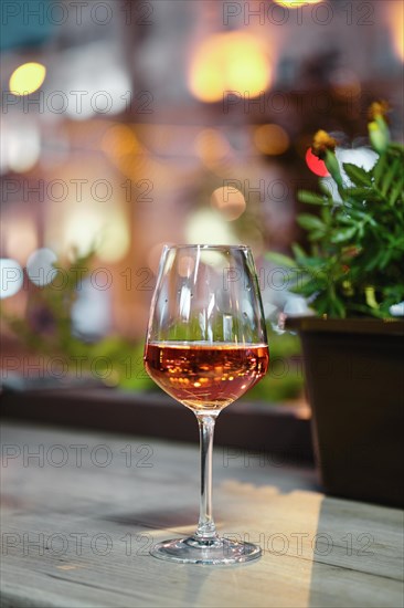 Glass of rose wine on bar counter with night city view on bacground