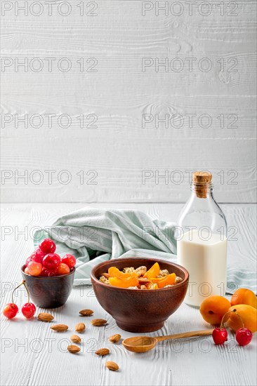 Muesli with apricots and almonds on white wooden table