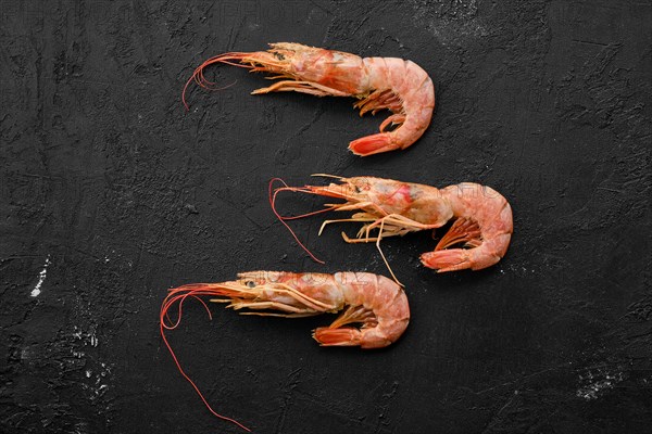 Three fresh raw prawns on wooden background